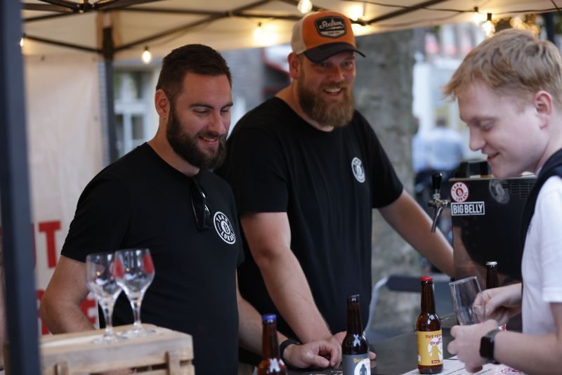 Gäste an Biertischen vor der Blaskapelle